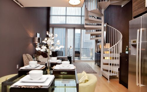 The Vue at Charlotte apartment interior with winding staircase, living area, couch, dining table, and floor to ceiling windows